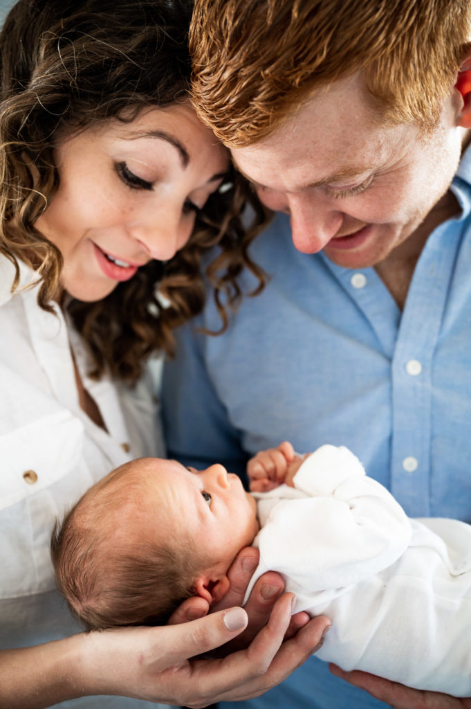 close up of parents holding baby and baby looking at parents
