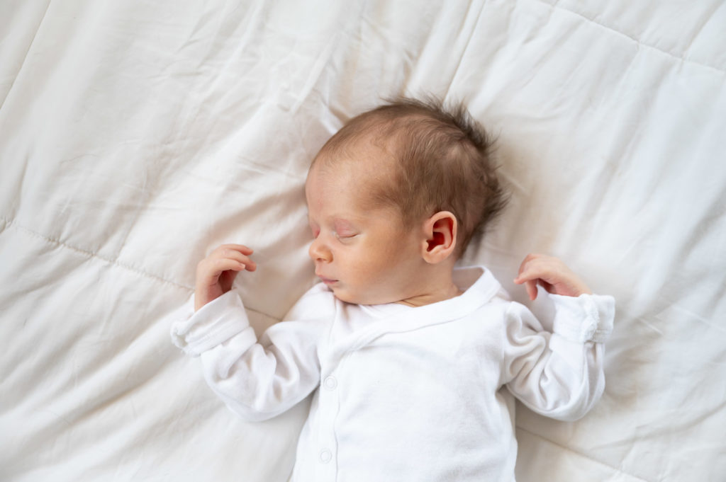 baby sleeping looking to the left on white blanket
