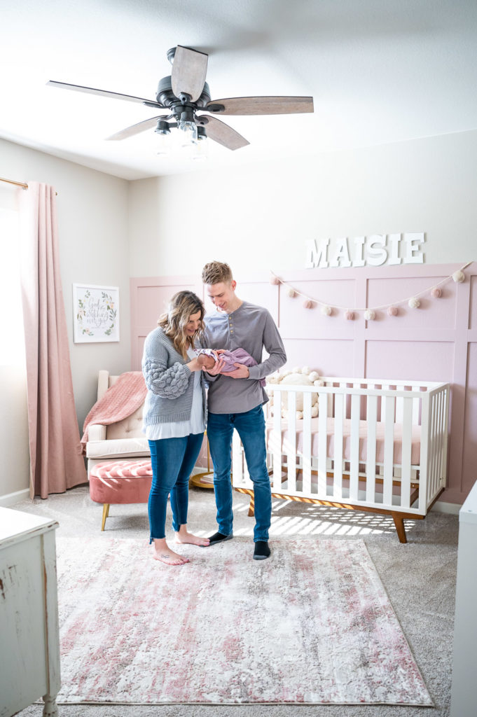 Family standing in nursery holding baby