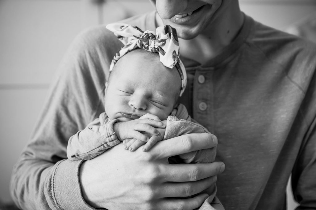 Black and white close up of baby's face in Dad's hands
