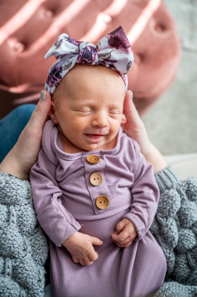 Newborn smiling in purple outfit
