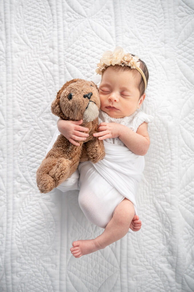 Baby girl wrapped up for newborn photos at home with stuffed lion
