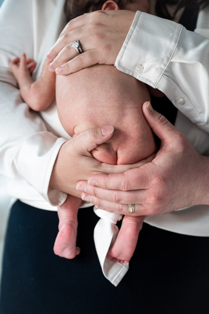 newborn baby bottom held in parents hands